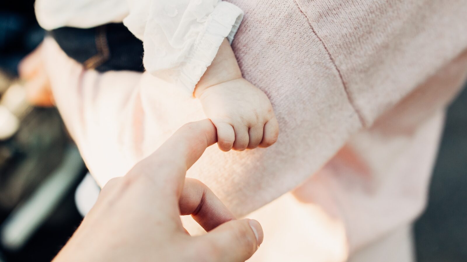 photo of parent holding baby's hand representing frequently asked questions about child support in Alberta