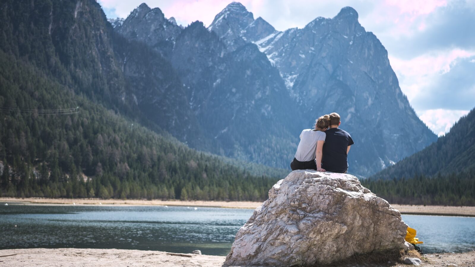 photo of couple sitting on rock looking at mountains representing adult interdependent relationships in alberta
