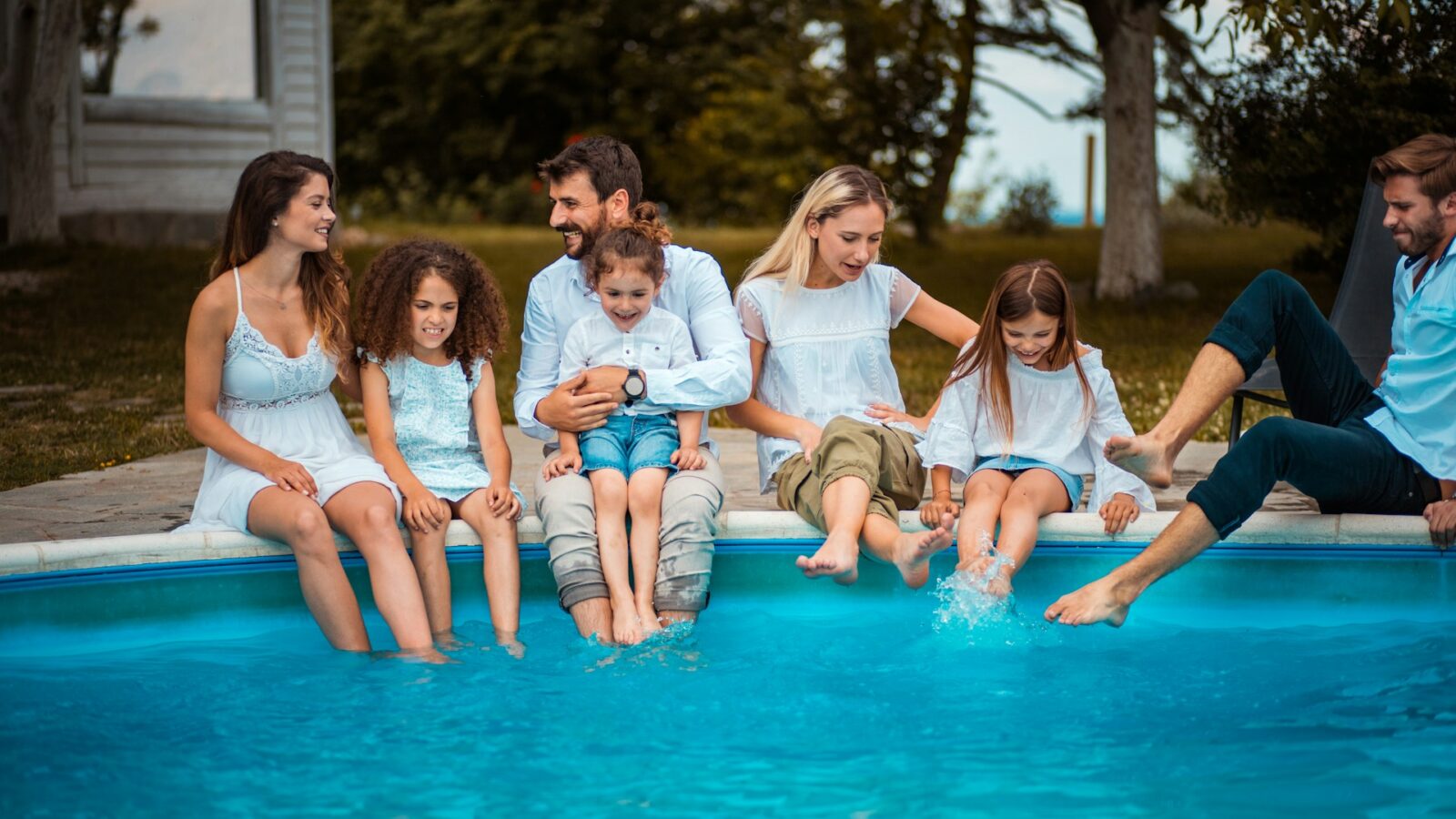 A large family with many children sitting at the edge of a pool, representing estate planning for blended families in Alberta.
