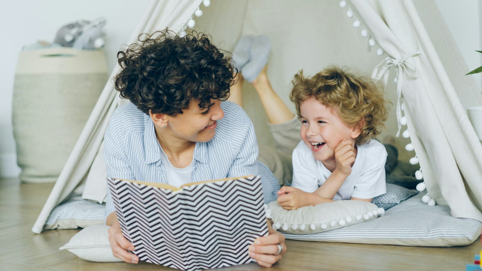 A young single parent with their child, reading a book together in a tent, representing common-law separation and parenting issues in Alberta