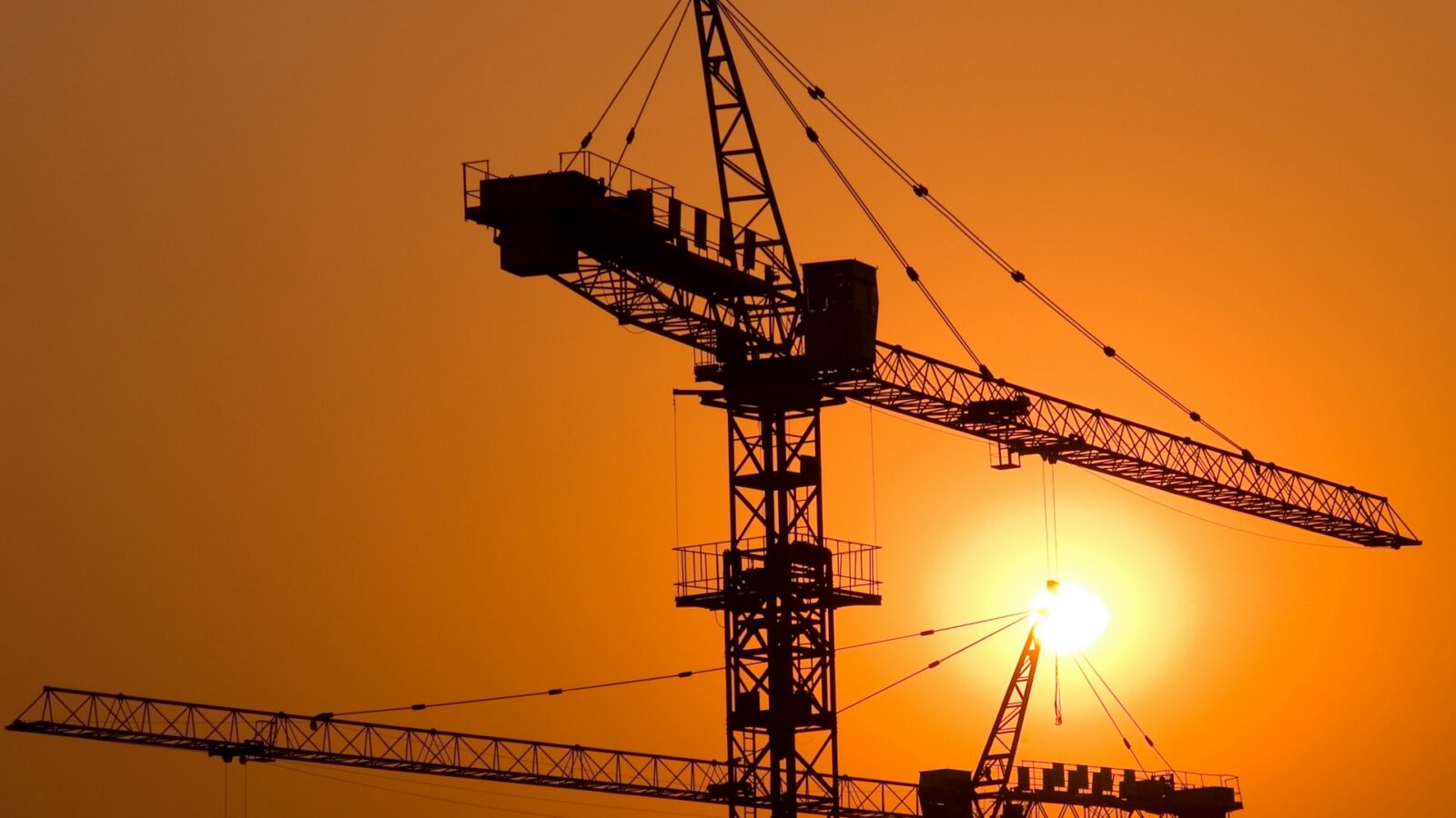 A sunset behind a silhouette of a construction crane, representing constsruction law and liability considerations in Alberta