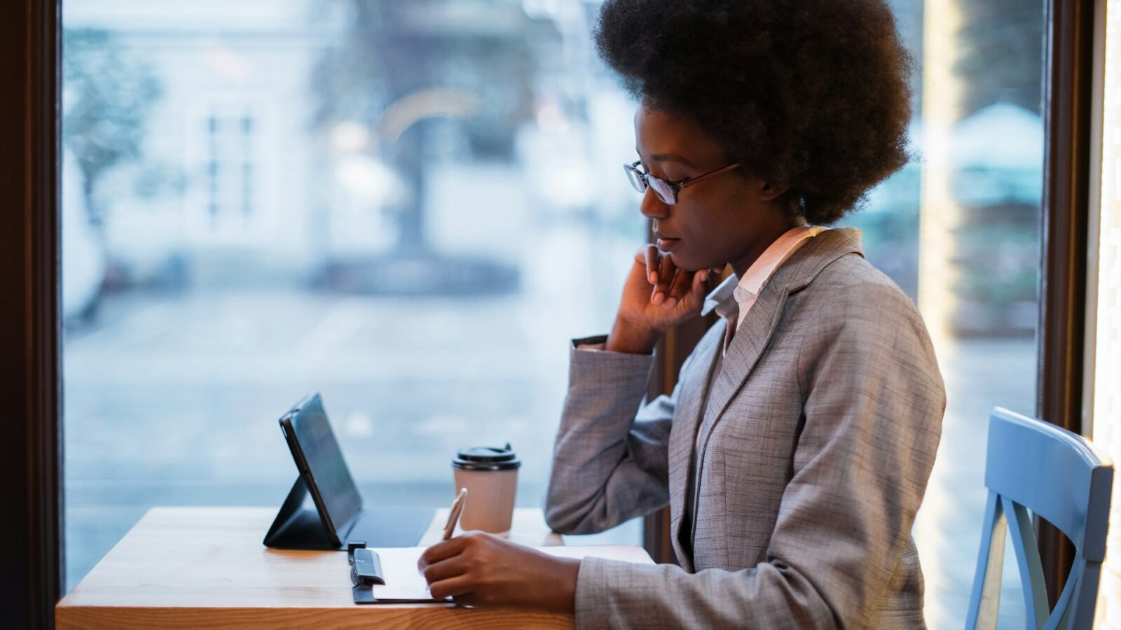 A young professional drafting an agreement by hand on a legal pad while working at a cafe, representing DIY separation agreements in Alberta family law