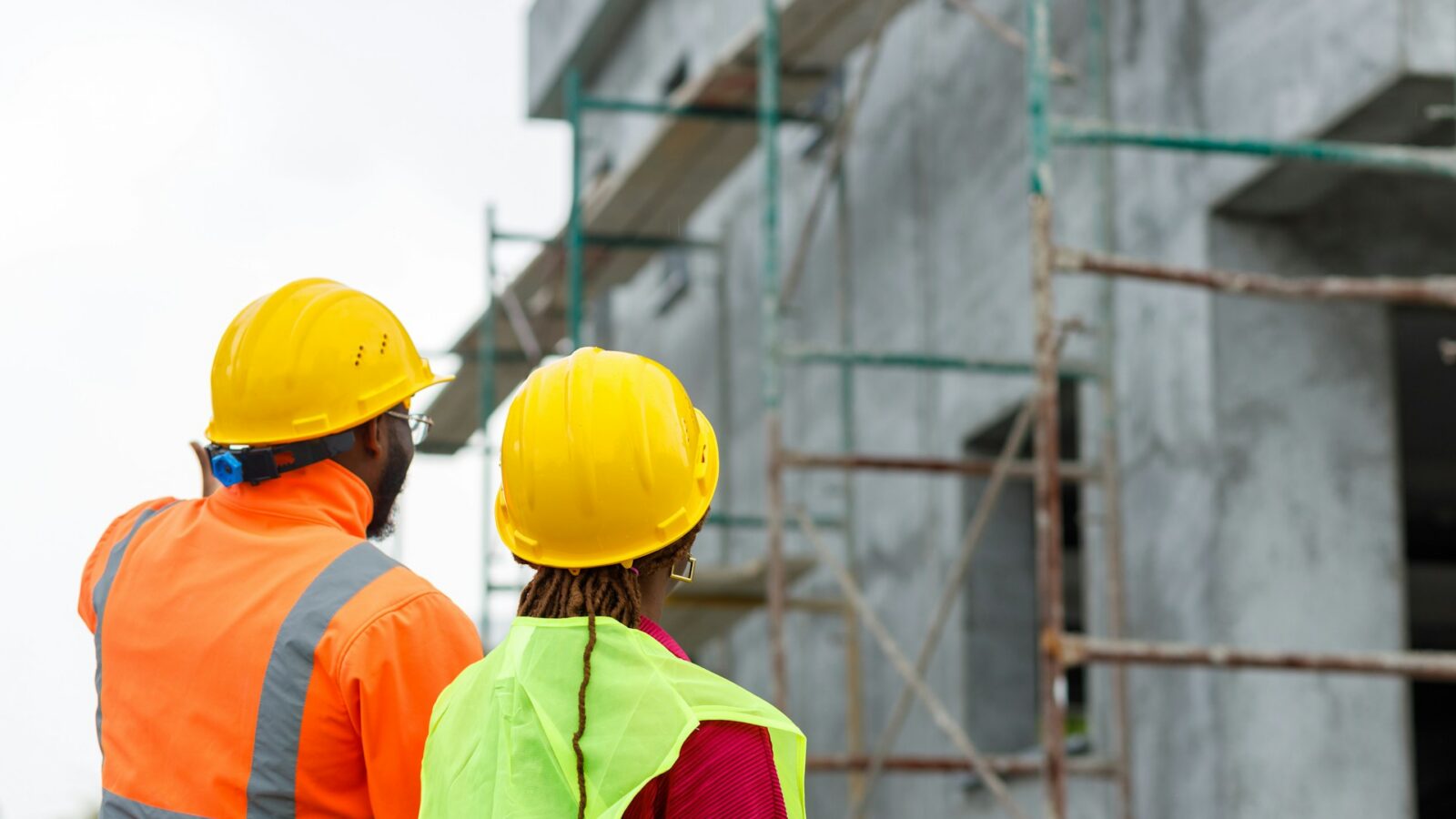Two construction workers looking up at a frame of a building, representing construction deals gone wrong and fraudulent conveyance claims in Alberta