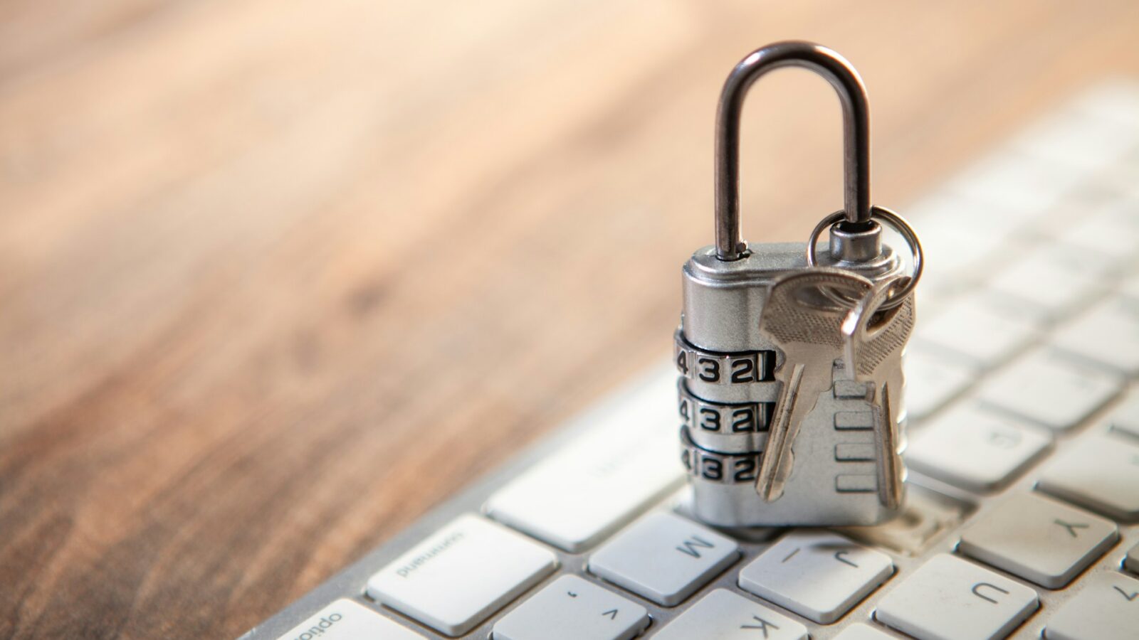 A combination lock set on a computer keyboard with a key dangling from the lock, representing digital assets after death.