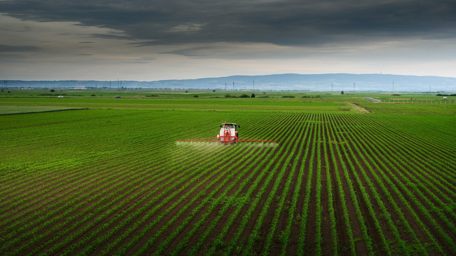 View of farm equipment spraying a large agricultural acreage, representing Alberta farms and rural property disputes.